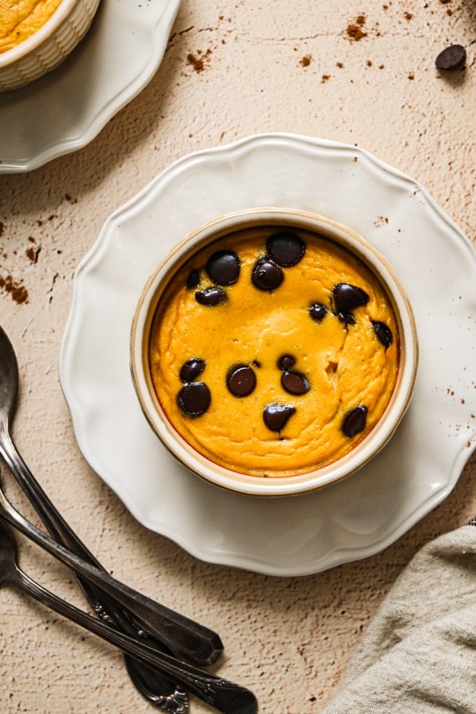Overhead view of baked yogurt topped with chocolate chips on a white plate.