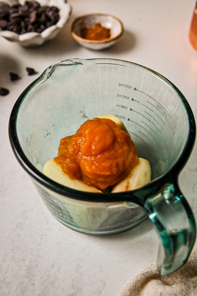 Ripe banana and pumpkin puree in a glass measuring cup.