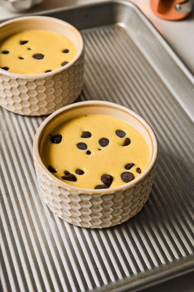 The batter poured into ramekins topped with chocolate chips before baking.
