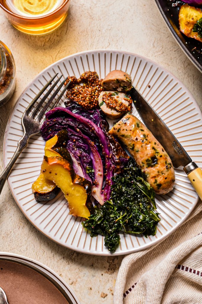 Overhead shot of chicken sausage with acorn squash and red cabbage in a plate.